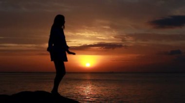 Deniz arka plan ile gün batımında sahilde dans kadın
