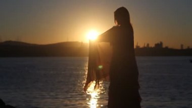 mutlu bir kadın deniz arka plan ile gün batımında sahilde dans