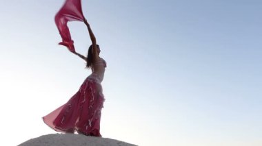 güzel kız pembe bir bez Rüzgar gökyüzü arka plan ile holding