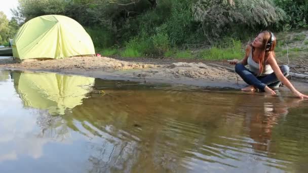 Girl with headphones by lake — Stock Video