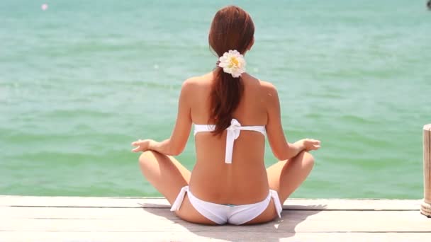 Kvinna på stranden nära havet mediterar — Stockvideo