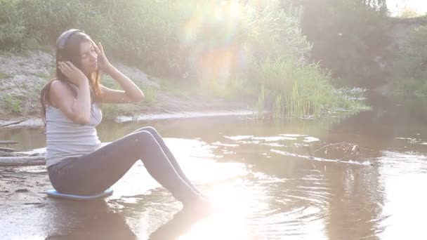 Chica con auriculares por el lago — Vídeos de Stock