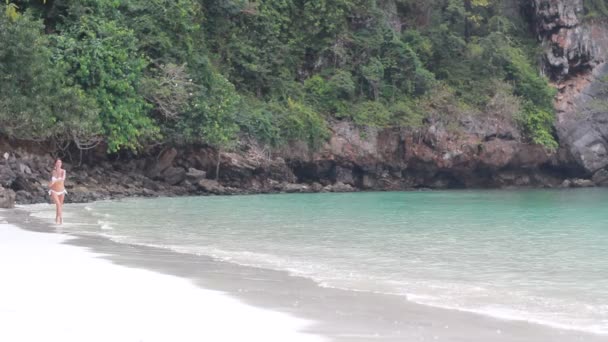 Una hermosa chica corre en la playa en bikini — Vídeo de stock