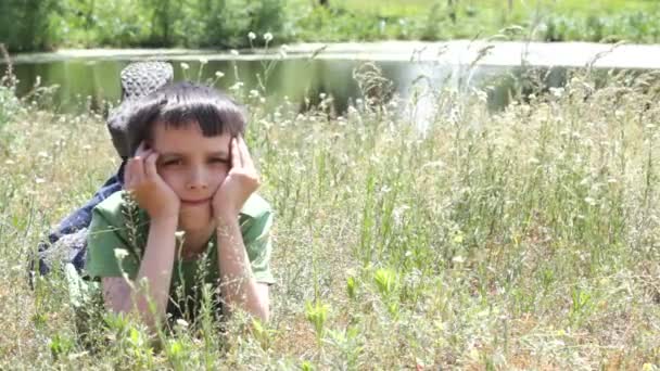 El chico yace en la hierba. Verano . — Vídeos de Stock