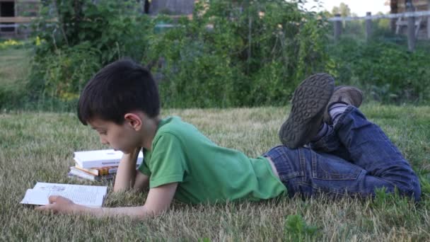 Хлопчик читає книгу на відкритому повітрі — стокове відео