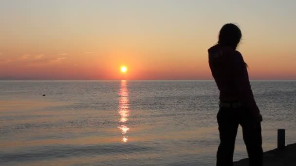 Щаслива жінка танцює на пляжі на заході сонця з морським фоном — стокове відео