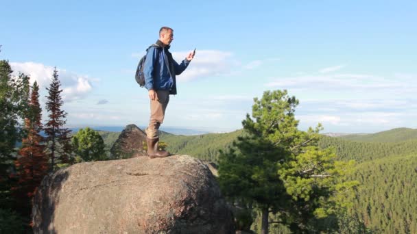 Vandrare med ryggsäck står på toppen av ett berg — Stockvideo