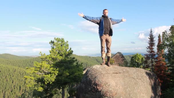 Πεζοπόρος με σακίδιο στέκεται στην κορυφή ενός βουνού — Αρχείο Βίντεο