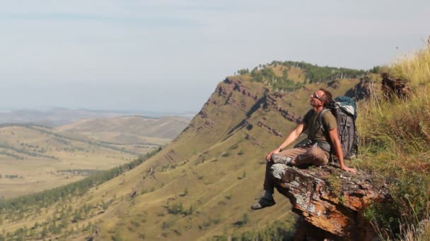 Turysta z plecaka stojący na szczycie góry — Wideo stockowe