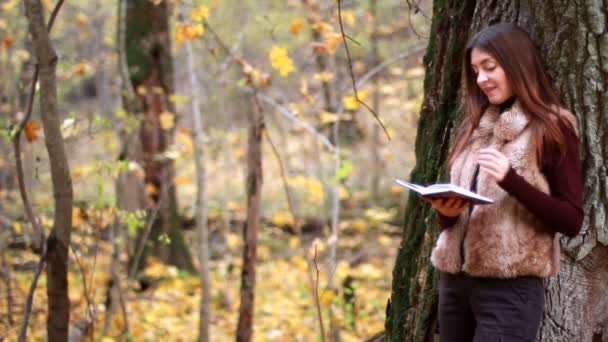 Menina bonita com livro no parque de outono — Vídeo de Stock