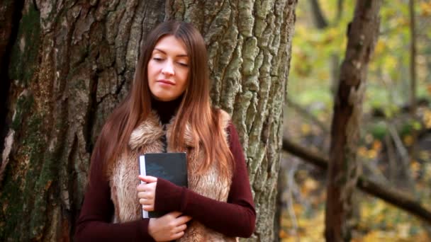 Menina bonita com livro no parque de outono — Vídeo de Stock