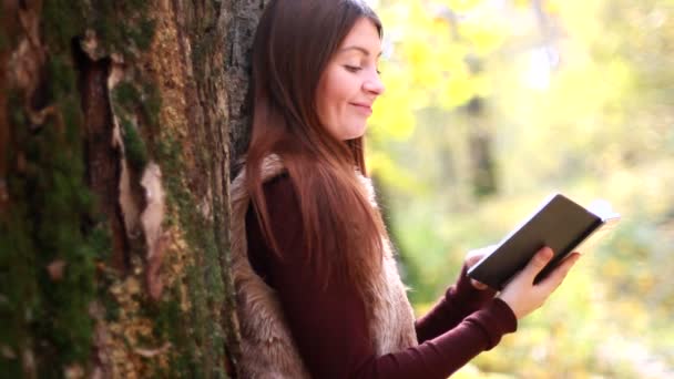Schönes Mädchen mit Buch im Herbstpark — Stockvideo