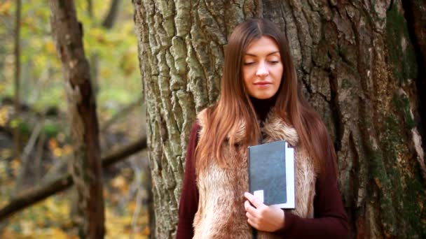 Beautiful girl with book in the autumn park — Stock Video