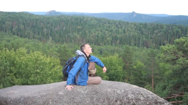 Wandelaar met rugzak zit op de top van een berg — Stockvideo