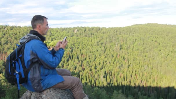 Escursionista con zaino seduto sulla cima di una montagna — Video Stock