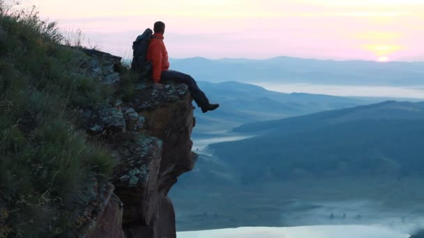 Turysta z plecaka siedzi na szczycie góry — Wideo stockowe