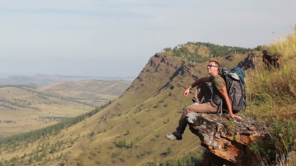 Vandrare med ryggsäck står på toppen av ett berg — Stockvideo