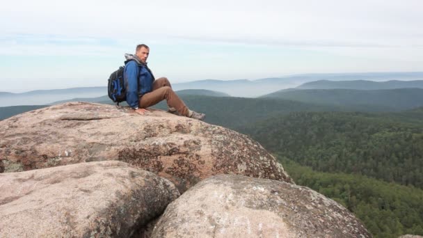 Hiker with backpack sitting on top of a mountain — Stock Video