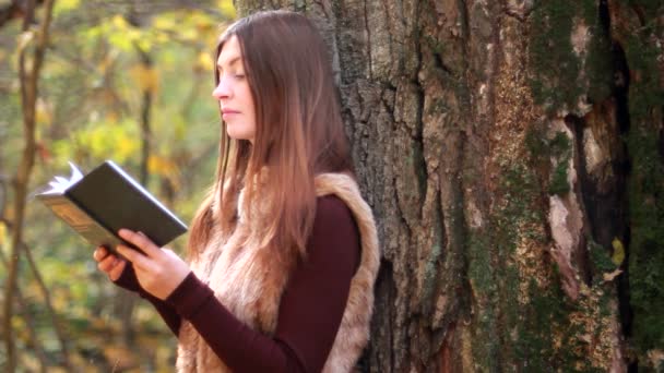 Vacker flicka med bok i höst park — Stockvideo