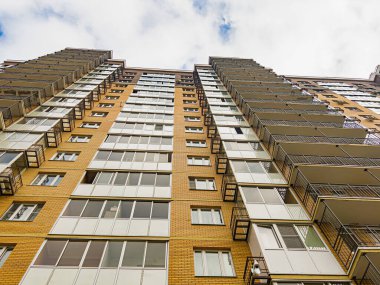 Pencereleri ve balkonları olan yeni bir apartmanın duvarı. Aşağıdan bir açıyla ateş ediyorlar..