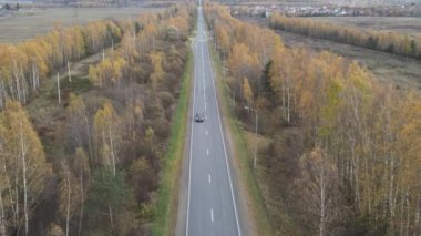 Sonbahar kırsal yollarında uçan bir dron. İki yönde de trafik var. Bir açıyla ateş etmek..
