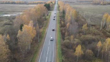 Sonbahar kırsal yollarında uçan bir dron. İki yönde de trafik var. Bir açıyla ateş etmek..