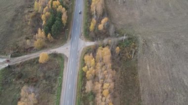 Sonbahar kırsal yollarında uçan bir dron. İki yönde de trafik var. Bir açıyla ateş etmek..