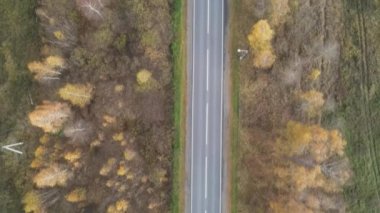 Sonbahar kırsal yollarında uçan bir dron. İki yönde de trafik var. Dik açılardan çekiliyor.