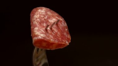 Çataldaki bir parça taze sosis koyu bir arka planda döner. Taze atıştırmalık konsepti.