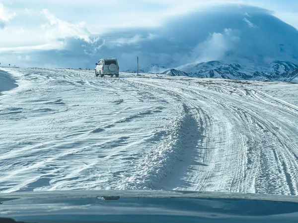 Suvは山の中の雪に覆われた道を運転しています 自動車旅行の概念 — ストック写真