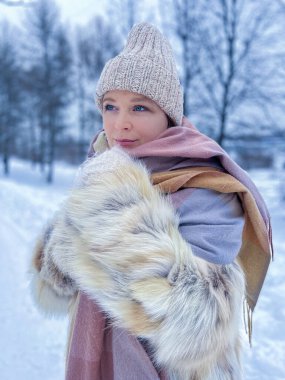 Bir kız kış ormanında arka planda poz veriyor. Parkta kış yürüyüşü konsepti.