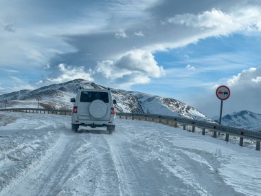 Bir SUV, kışın karla kaplı dağ yolu boyunca 