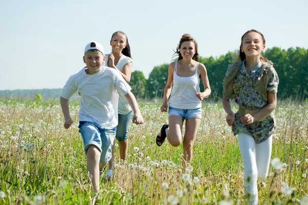 Women with teens running in grass — Stock Photo, Image