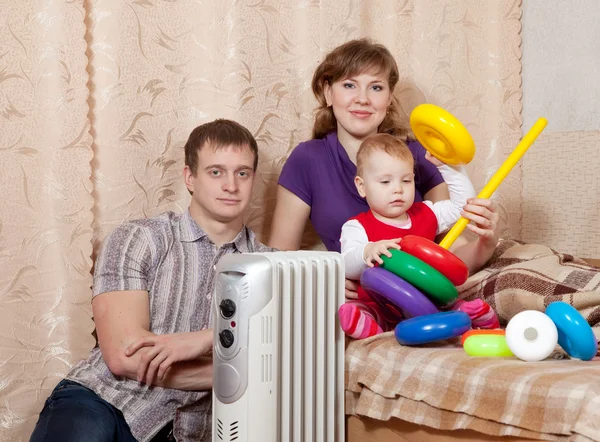 Pais e criança perto do radiador quente — Fotografia de Stock