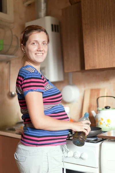 Mulher grávida cozinha em sua cozinha — Fotografia de Stock