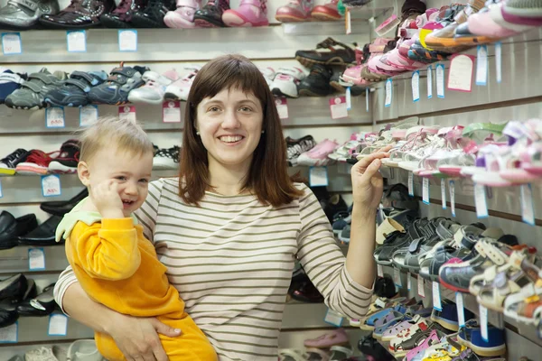 Счастливая мать с ребенком выбирает детскую обувь — стоковое фото