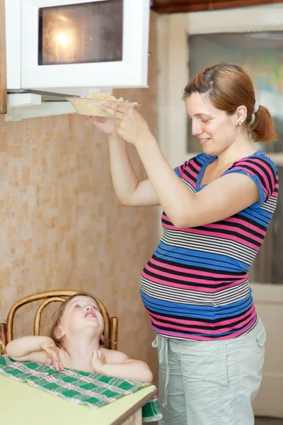 Pregnant woman warms up food — Stock Photo, Image