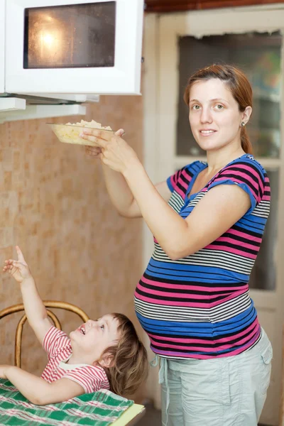 Donna incinta riscalda il cibo — Foto Stock