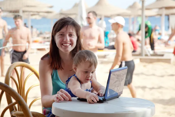 Madre feliz y niño pequeño con portátil en la playa —  Fotos de Stock