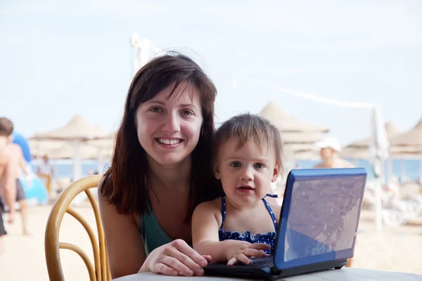 Madre feliz y niño pequeño con portátil en la playa — Foto de Stock