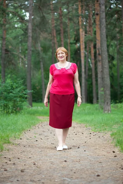 Mogen kvinna promenader i skogen — Stockfoto