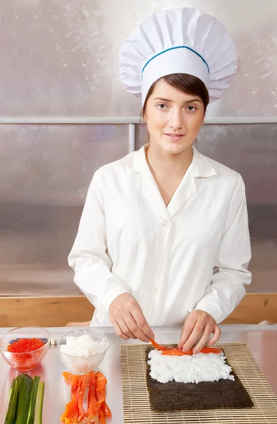 woman making sushi rolls in kitchen