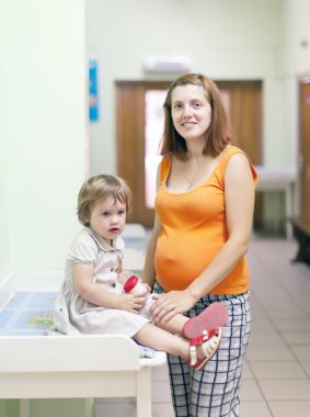 pregnant woman with child at the clinic clipart