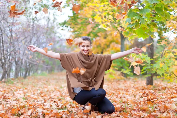 Woman throws autumn leaves