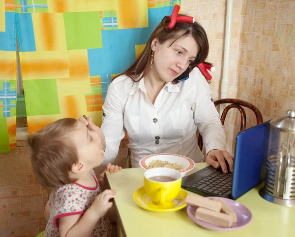 Mamma matar barn och använder latop — Stockfoto