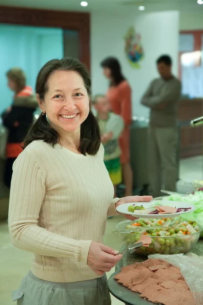 Mulher escolhe lanche em buffet — Fotografia de Stock