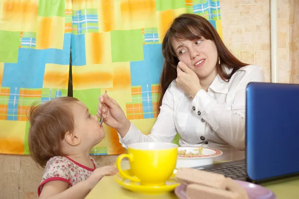 Geschäftsfrau füttert Baby und spricht per Handy — Stockfoto