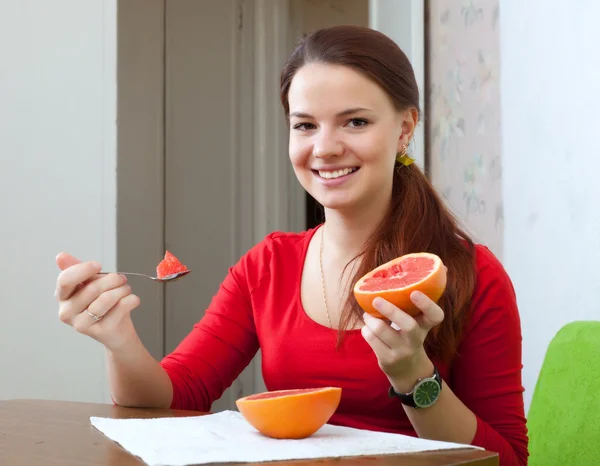 Mulher de vermelho come toranja em casa — Fotografia de Stock