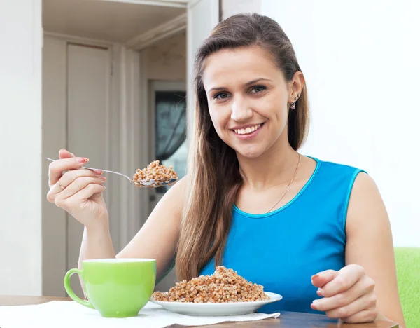 Girl eats buckwheat with spoon — Stock Photo, Image