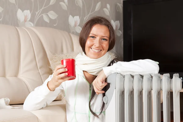 Mulher sorridente perto do radiador quente — Fotografia de Stock